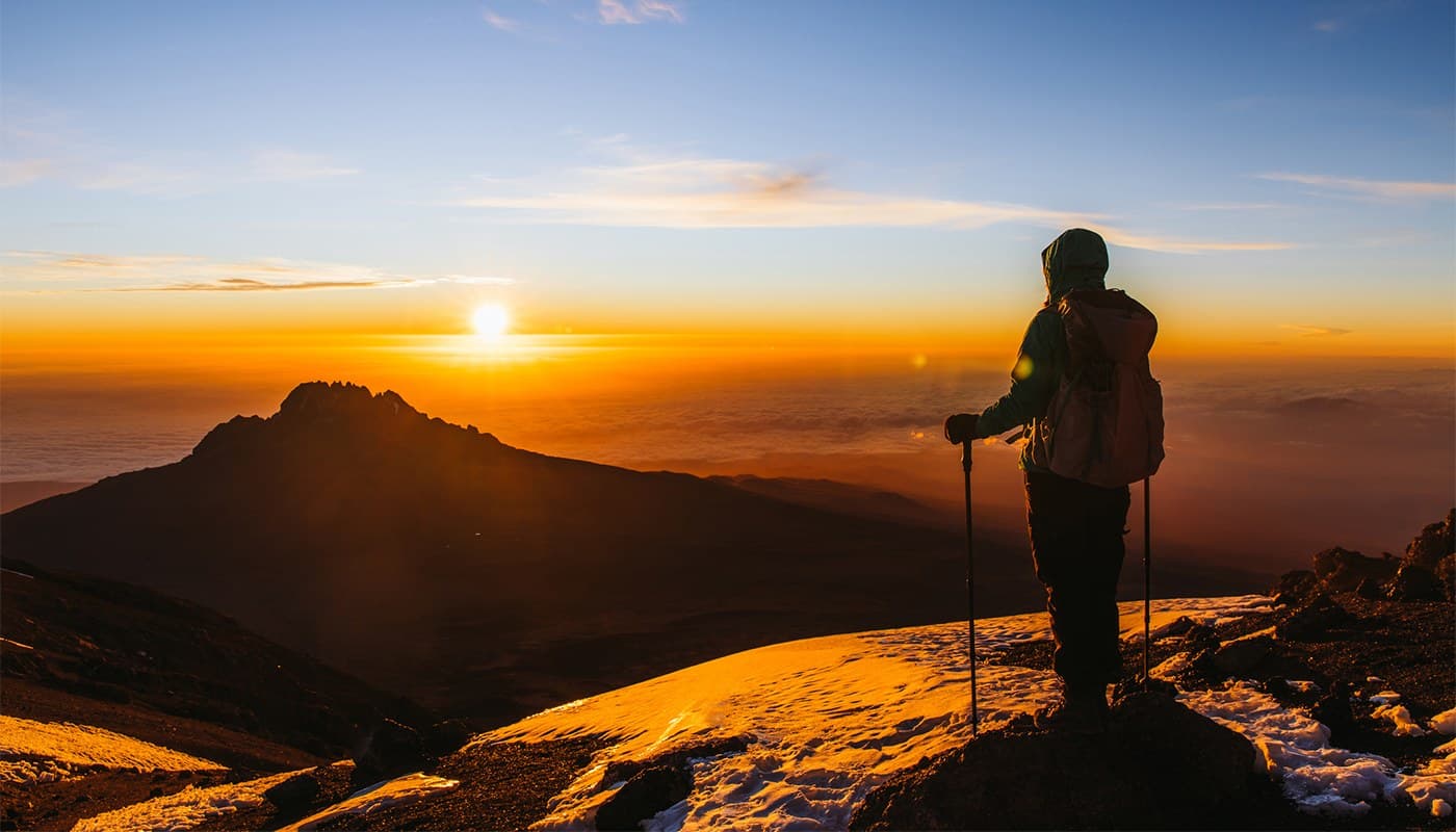 A trekker silhouetted against sunrise high on Kilimanjaro